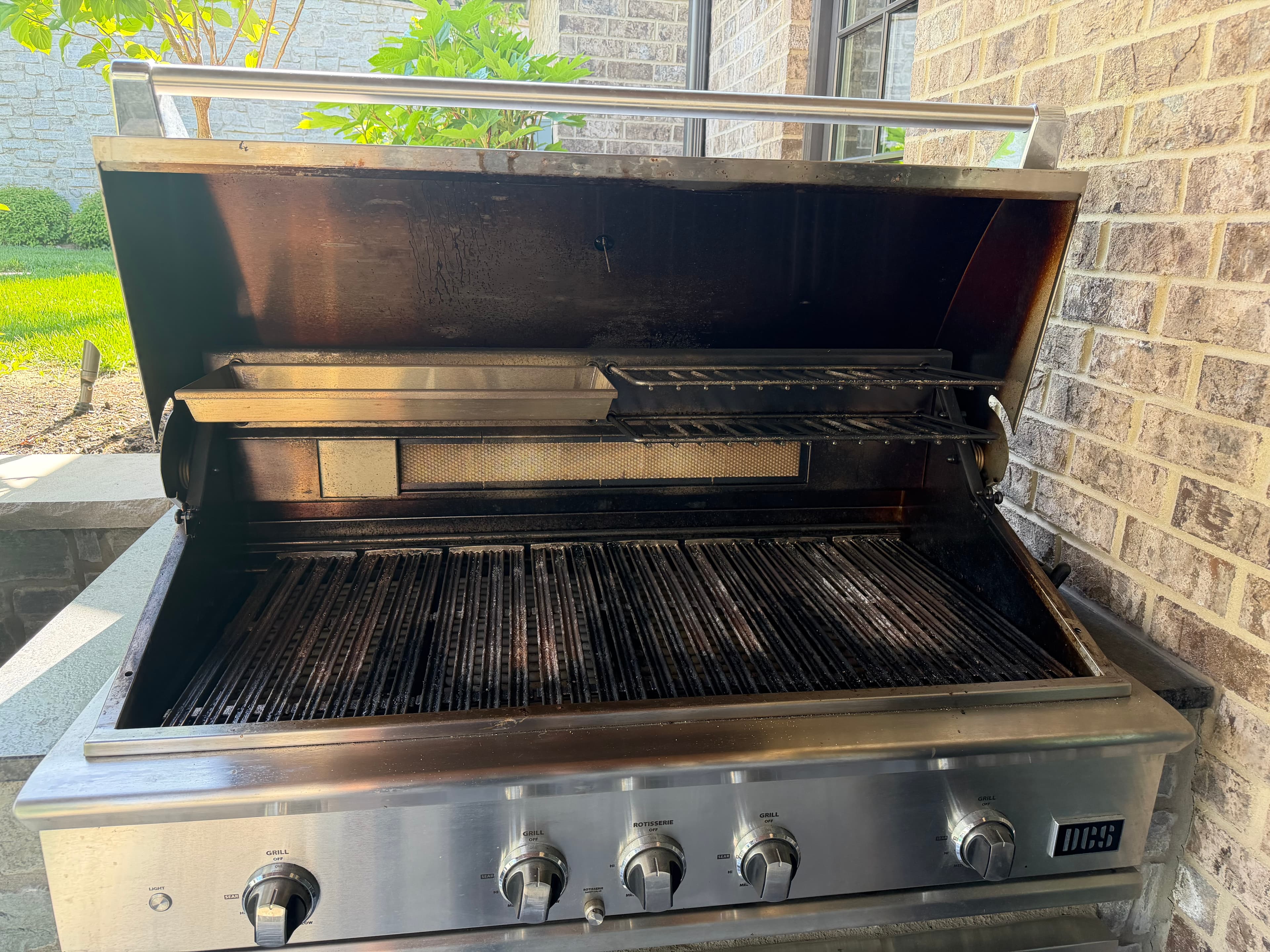 Before: a DCS built-in grill blackened with soot and heavy carbon buildup across the grates and cookbox