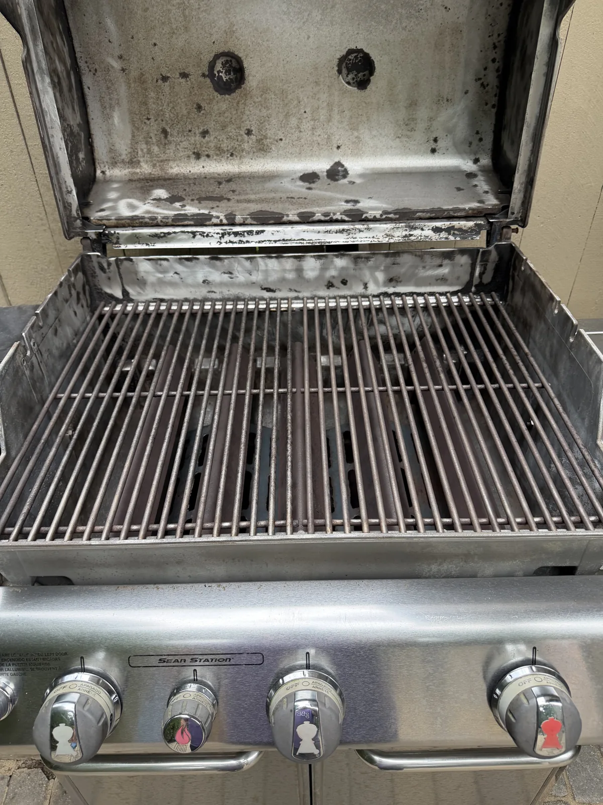 Before: Weber Genesis gas grill with Sear Station, lid open on a Mt. Lookout deck — discolored hood interior, soot-stained cookbox, and grease-darkened grates before service