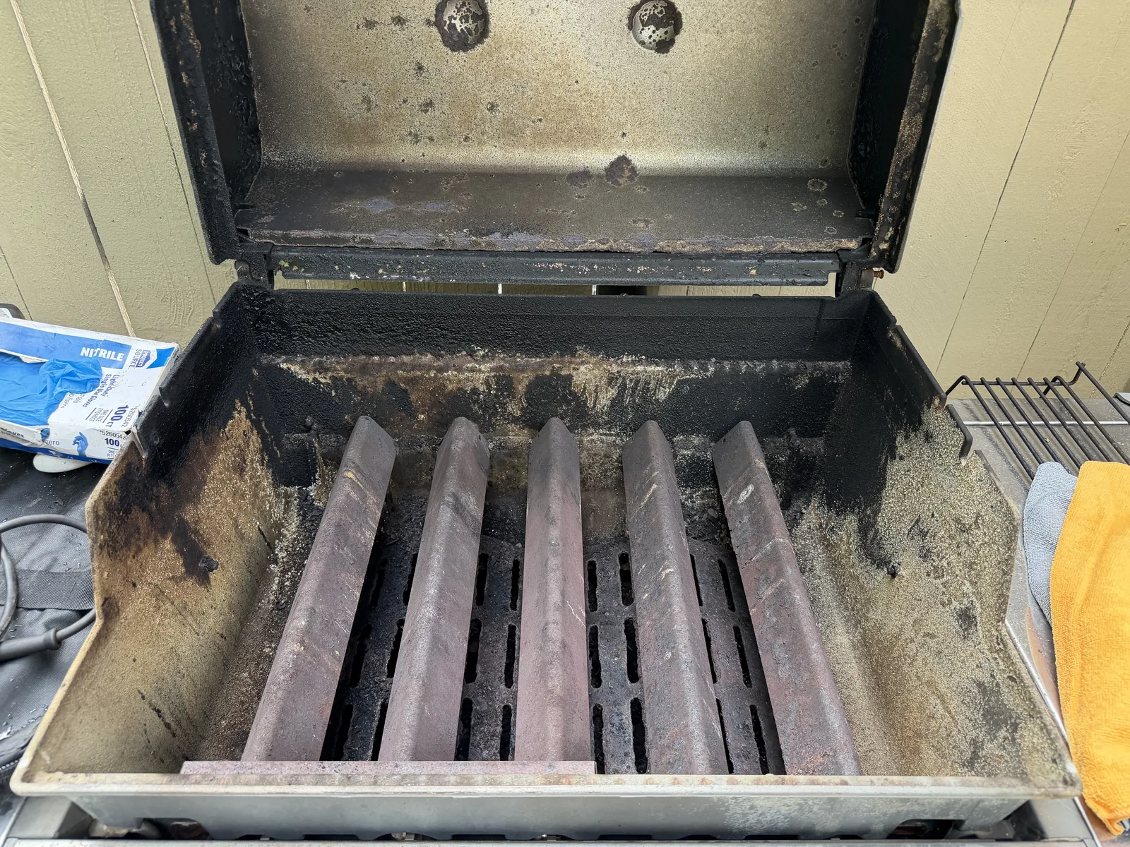 Before: the Genesis cookbox mid-strip — flavorizer bars crusted with carbon and the firebox walls caked in baked-on grease