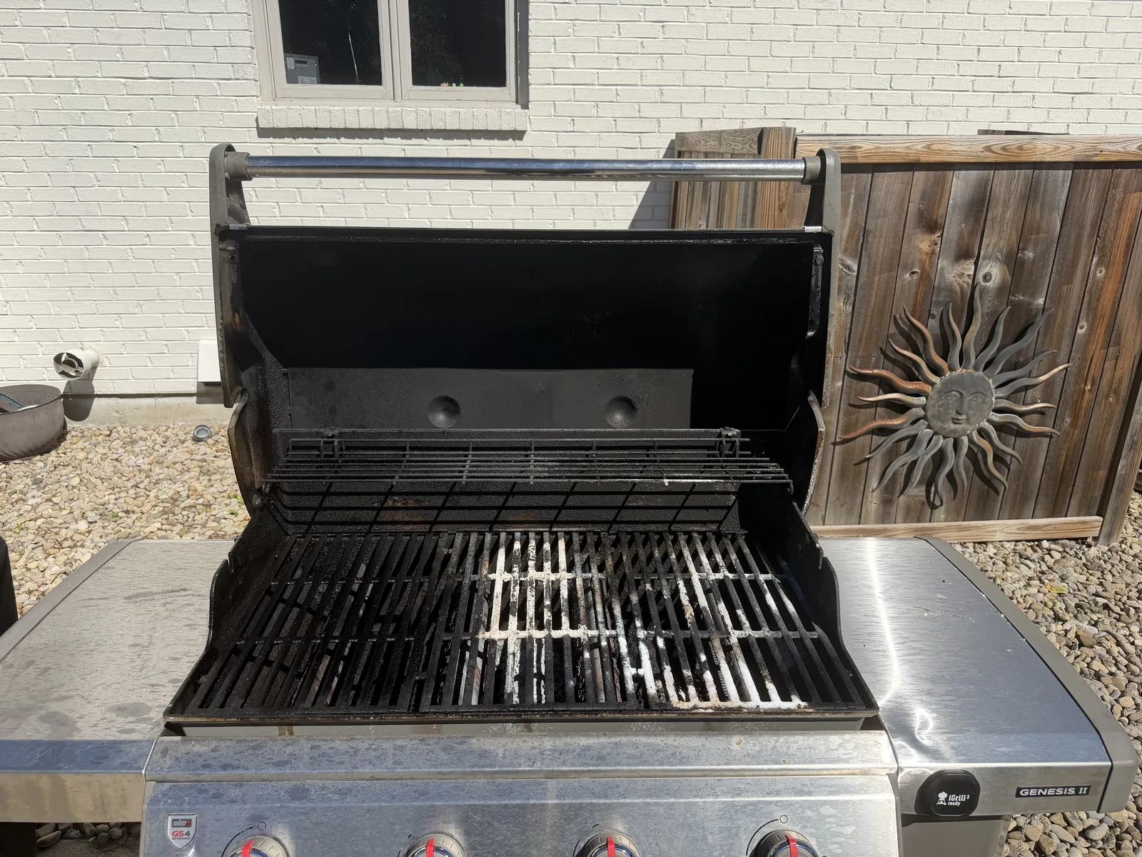 Before: a 12-year-old Weber Genesis II gas grill in a Mason backyard, lid open — grease-darkened grates and a soot-stained hood interior before service